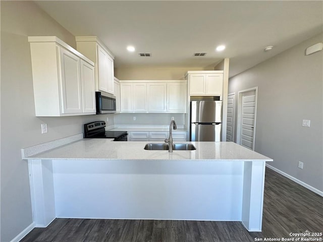 kitchen featuring kitchen peninsula, light stone counters, stainless steel appliances, sink, and white cabinetry