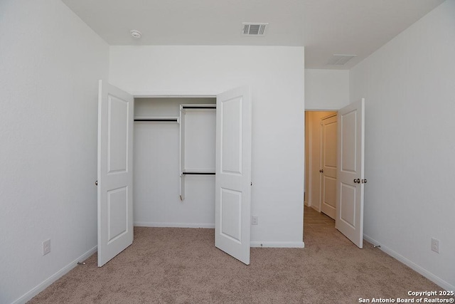 unfurnished bedroom with a closet and light colored carpet