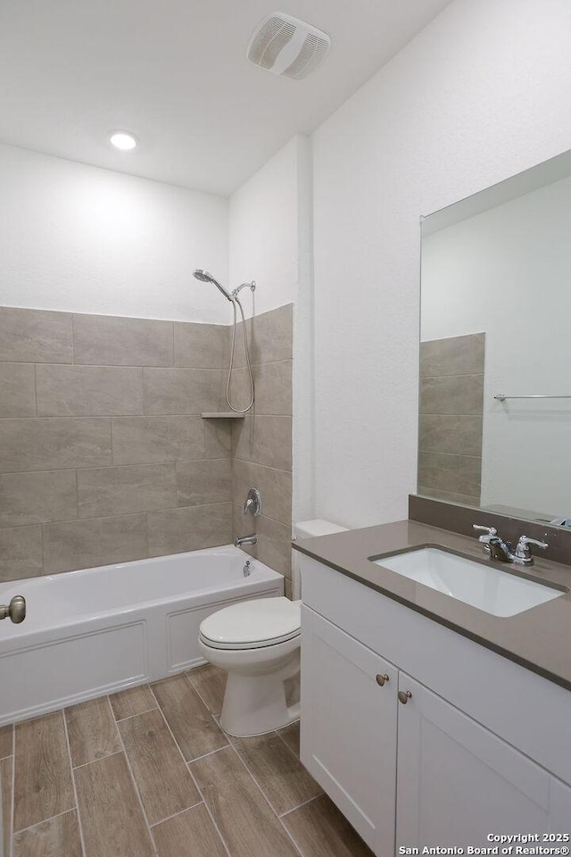 full bathroom with tiled shower / bath combo, toilet, and vanity