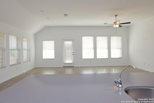 living room featuring ceiling fan, lofted ceiling, sink, and light hardwood / wood-style flooring