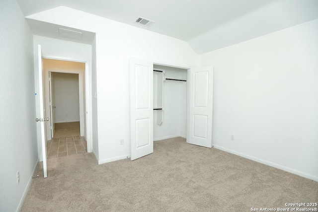 unfurnished bedroom with a closet, light colored carpet, and lofted ceiling