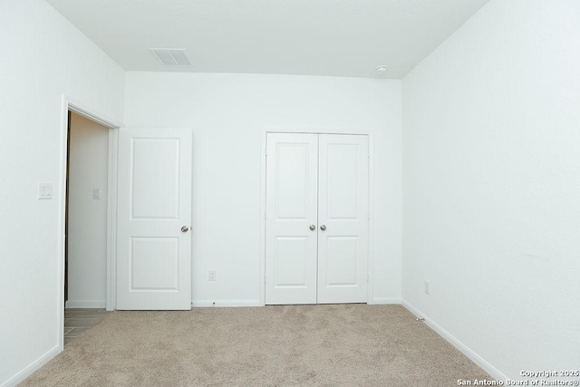 unfurnished bedroom featuring a closet and light colored carpet