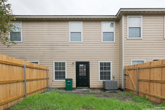 back of house with cooling unit and a yard