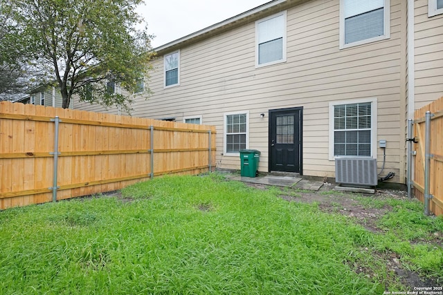 back of property featuring a lawn and central AC