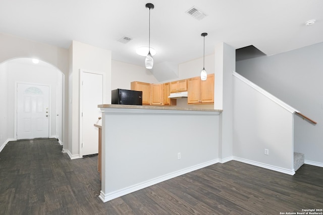 kitchen with black refrigerator, light brown cabinets, kitchen peninsula, and dark wood-type flooring