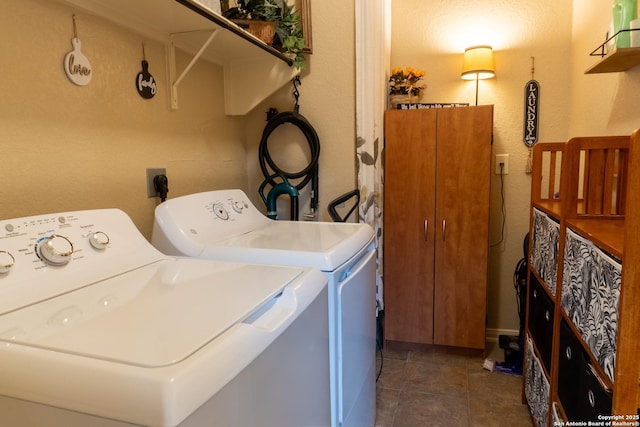 clothes washing area featuring dark tile patterned flooring and washer and clothes dryer