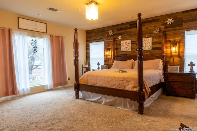 bedroom featuring carpet flooring, wood walls, and multiple windows