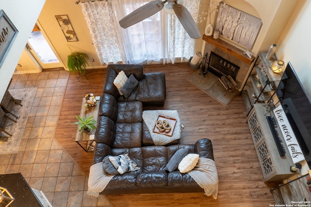 living room with a tile fireplace and ceiling fan