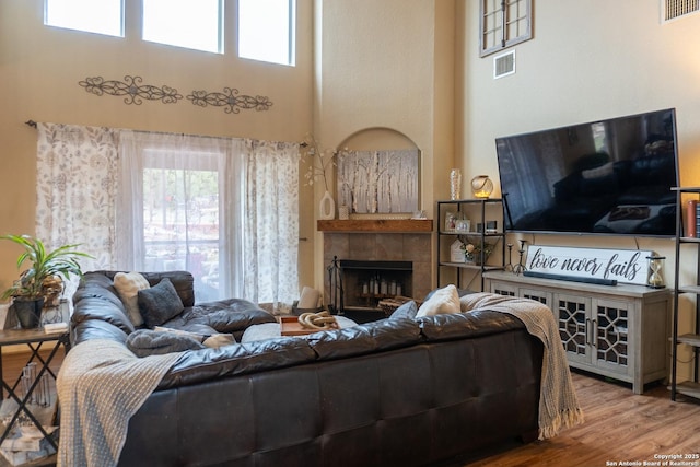 living room featuring a fireplace, a towering ceiling, and hardwood / wood-style floors