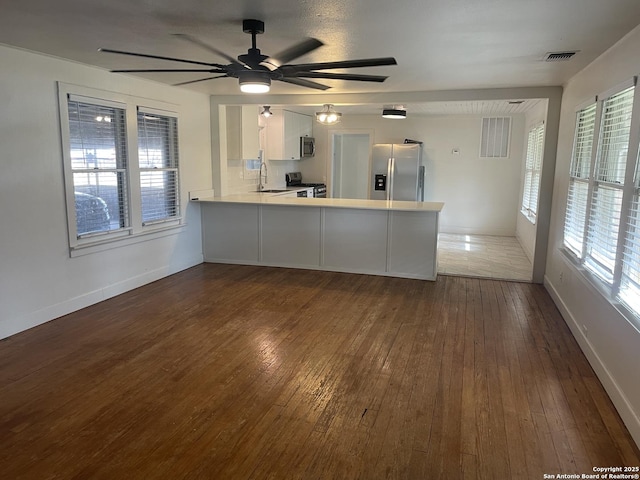 kitchen with kitchen peninsula, white cabinetry, dark wood-type flooring, and stainless steel appliances