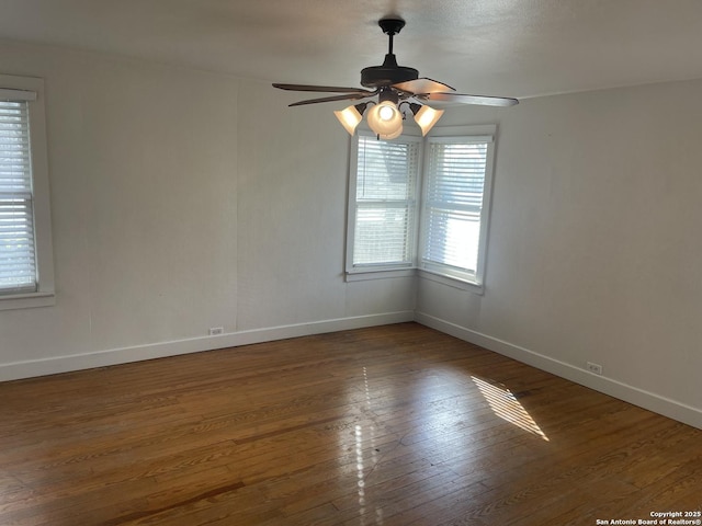 spare room with dark hardwood / wood-style flooring, ceiling fan, and plenty of natural light