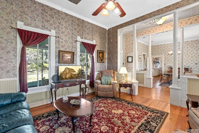 living room with decorative columns, ceiling fan, ornamental molding, and light wood-type flooring