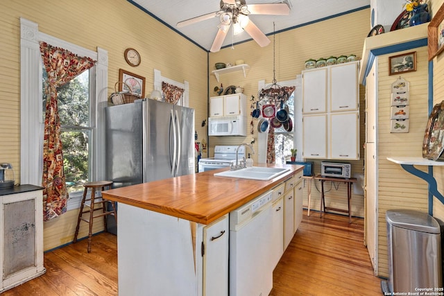 kitchen with white appliances, white cabinets, a center island with sink, sink, and light hardwood / wood-style flooring