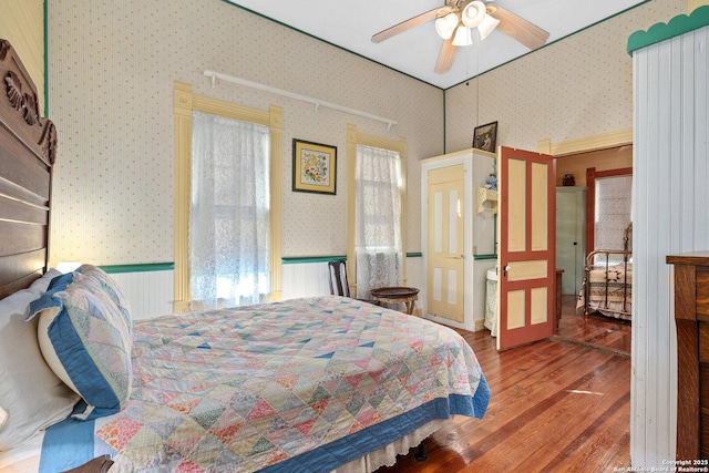 bedroom with hardwood / wood-style flooring, ceiling fan, and multiple windows