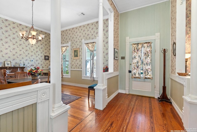 entrance foyer featuring a chandelier, hardwood / wood-style flooring, decorative columns, and ornamental molding