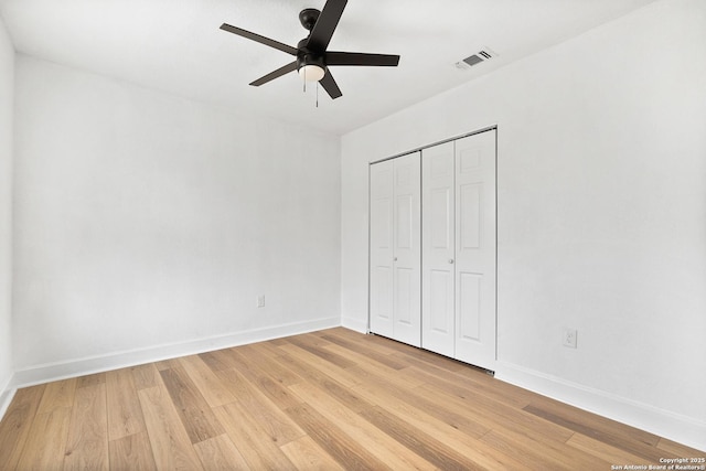 unfurnished bedroom featuring ceiling fan, a closet, and light wood-type flooring