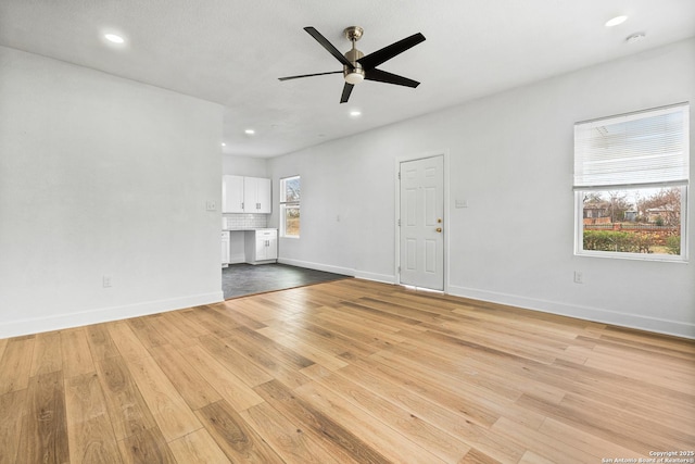 unfurnished living room featuring ceiling fan, plenty of natural light, and light wood-type flooring