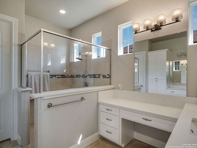 bathroom featuring tile patterned floors, a shower with door, and vanity