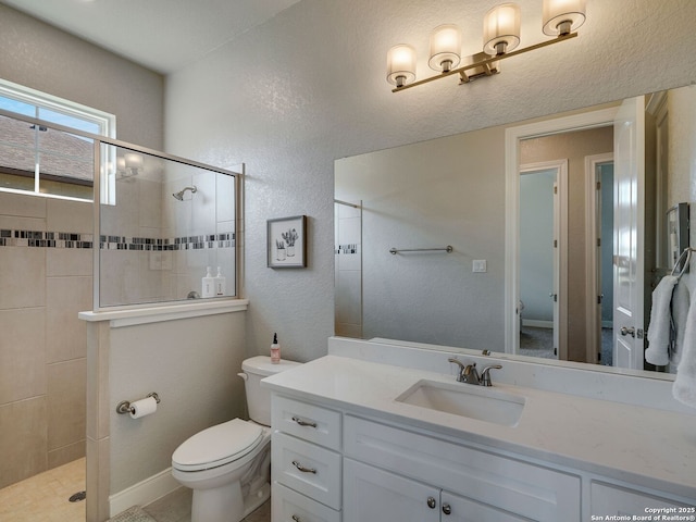 bathroom with toilet, vanity, and tiled shower