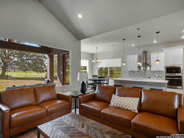 living room with sink, parquet flooring, a notable chandelier, vaulted ceiling, and a textured ceiling