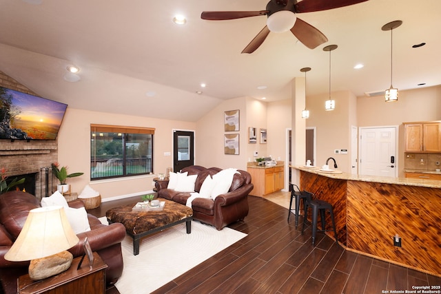 living room featuring ceiling fan, a fireplace, vaulted ceiling, and sink