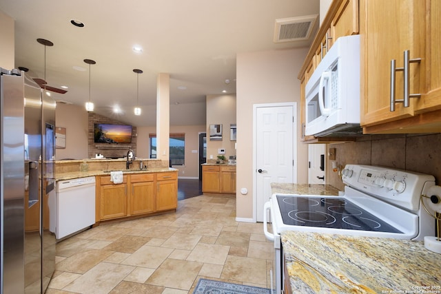 kitchen with white appliances, sink, light stone countertops, decorative light fixtures, and kitchen peninsula