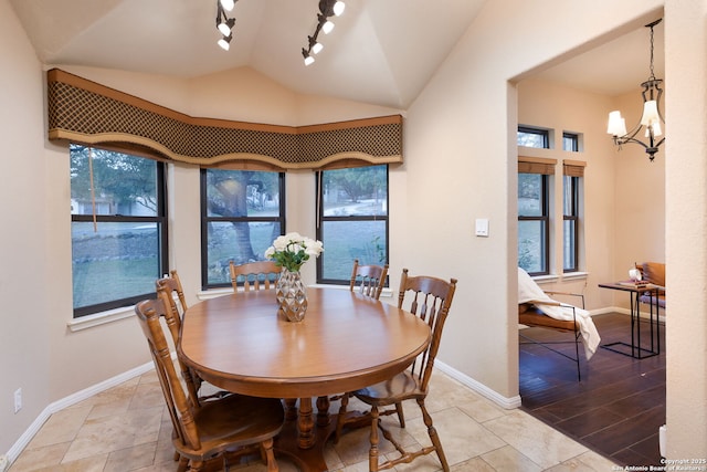 dining area featuring a notable chandelier, rail lighting, and vaulted ceiling