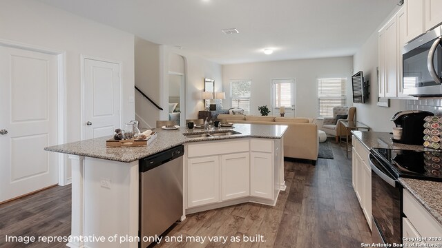 kitchen with a kitchen island with sink, sink, appliances with stainless steel finishes, dark hardwood / wood-style flooring, and white cabinetry