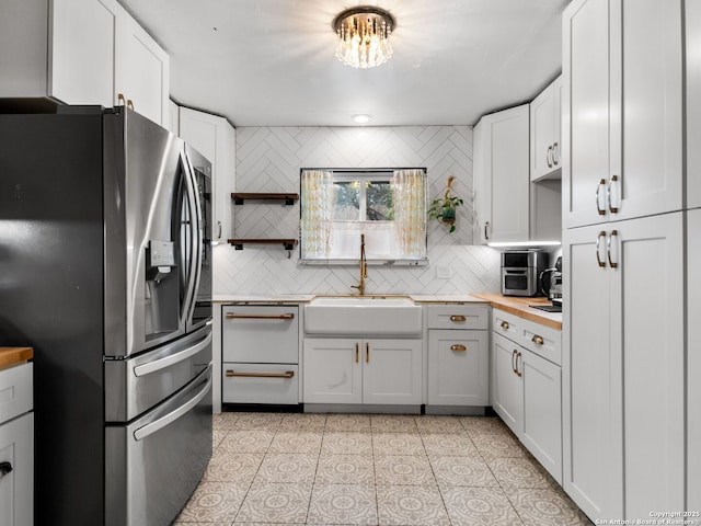 kitchen with white cabinets, appliances with stainless steel finishes, decorative backsplash, and sink