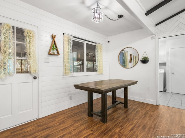 dining space featuring wood walls, dark hardwood / wood-style floors, beam ceiling, and a chandelier