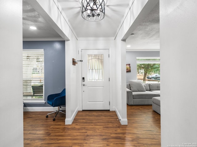 foyer entrance featuring plenty of natural light, dark wood-type flooring, a textured ceiling, and a notable chandelier