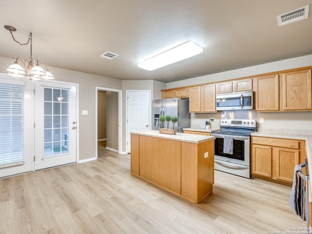 kitchen featuring a textured ceiling, stainless steel appliances, pendant lighting, a notable chandelier, and a kitchen island