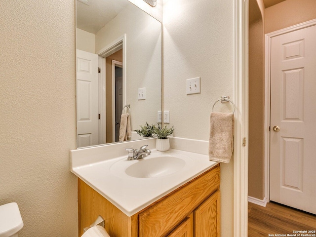 bathroom with wood-type flooring, vanity, and toilet