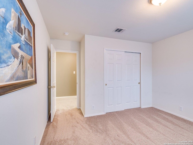 unfurnished bedroom featuring light carpet and a closet