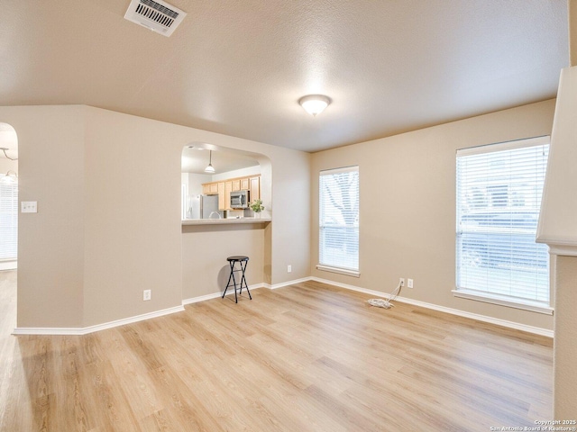 unfurnished living room with a textured ceiling and light wood-type flooring