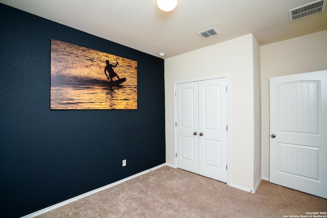 unfurnished bedroom with light carpet and a closet