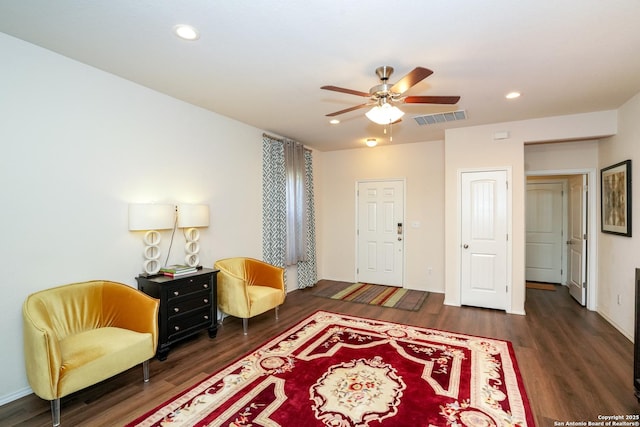 sitting room with ceiling fan and dark wood-type flooring