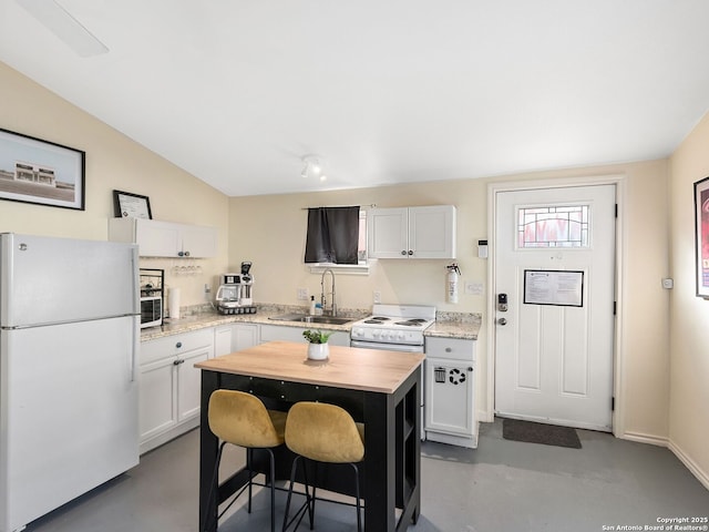 kitchen featuring sink, a kitchen island, a kitchen breakfast bar, white appliances, and white cabinets