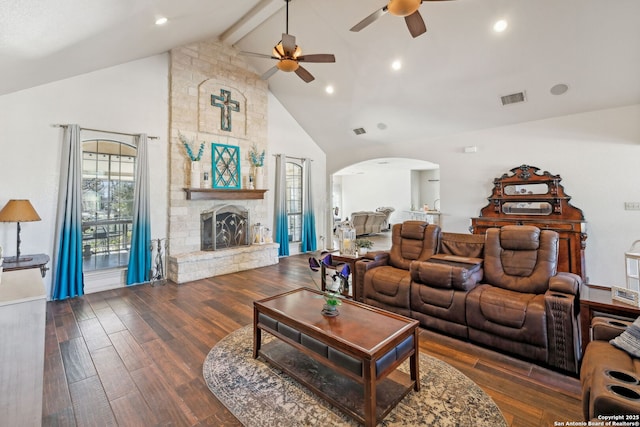 living room featuring high vaulted ceiling, a stone fireplace, ceiling fan, beam ceiling, and dark hardwood / wood-style flooring