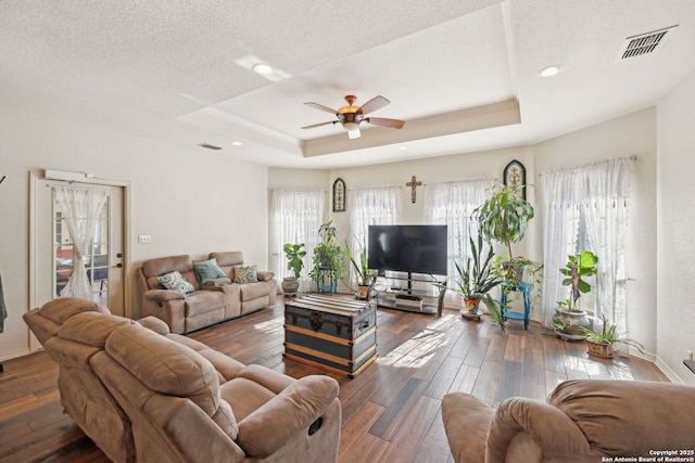 living room featuring a textured ceiling, dark hardwood / wood-style flooring, a raised ceiling, and ceiling fan