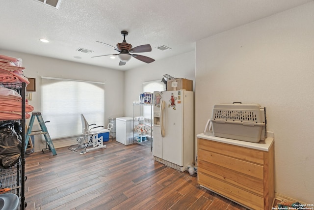 interior space featuring dark wood-type flooring, ceiling fan, white fridge with ice dispenser, a textured ceiling, and fridge