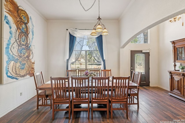 dining area with crown molding, dark hardwood / wood-style floors, and an inviting chandelier