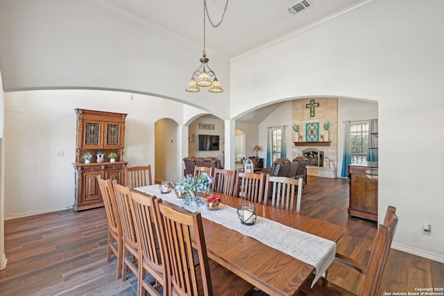 dining room featuring a notable chandelier, a large fireplace, dark hardwood / wood-style flooring, and crown molding