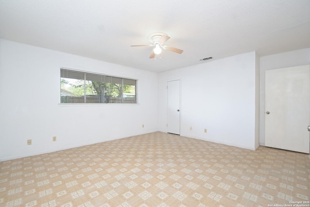 empty room with ceiling fan and a textured ceiling