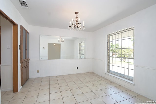 unfurnished room featuring light tile patterned floors and a notable chandelier