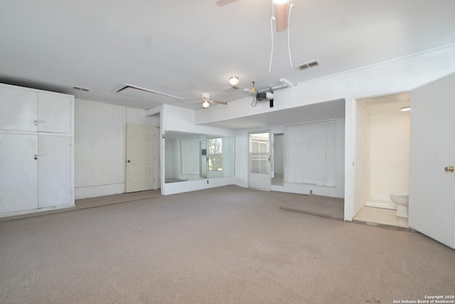 basement with ceiling fan and light colored carpet