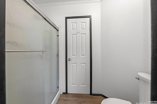 bathroom with hardwood / wood-style flooring, a shower with door, and crown molding