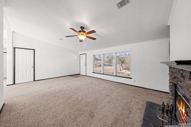 unfurnished living room featuring a stone fireplace, ceiling fan, crown molding, and carpet floors