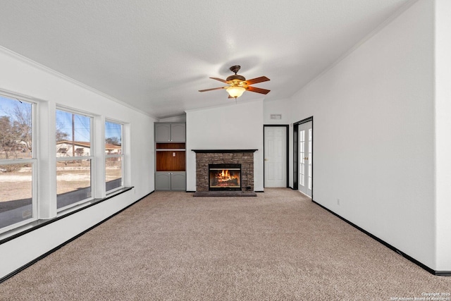 unfurnished living room with light carpet, a textured ceiling, baseboard heating, ceiling fan, and a fireplace