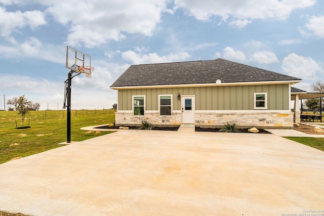 back of house with basketball court and a yard